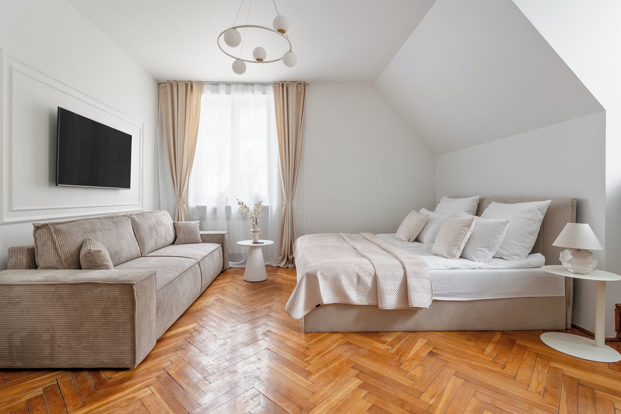 Een moderne slaapkamer met een bank, een bed, een televisie en een kroonluchter.