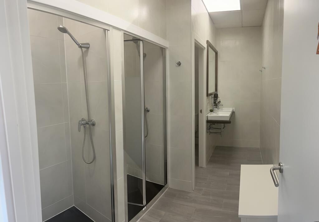 Un baño moderno con cabina de ducha de vidrio, un lavabo blanco y un espejo.