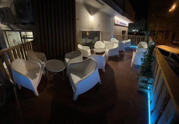 A rooftop terrace with white plastic chairs and tables, a wooden railing, and a small plant arrangement. - ALBERGUE AS POZAS TERMAIS (Caldas de Reis)