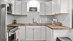 A modern kitchen with white cabinetry, a wooden countertop, and a built-in oven. - Billings Homesteader: Near Hospital, Trails, Stores, and Entertainment (Billings)