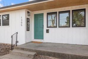 Un bâtiment blanc avec une porte verte, portant le numéro 1305, et une enseigne sur laquelle on peut lire « DOMICILE ».