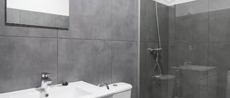 A modern bathroom with a white sink, mirror, and shower.