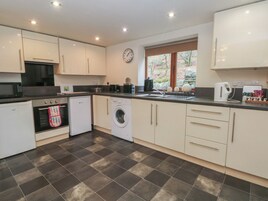 A modern kitchen with white cabinets, a microwave, a washing machine, and a sink.