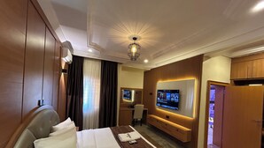 Ein Hotelzimmer mit Bett, Wand-Fernseher, Schreibtisch mit Stuhl und Kleiderschrank.