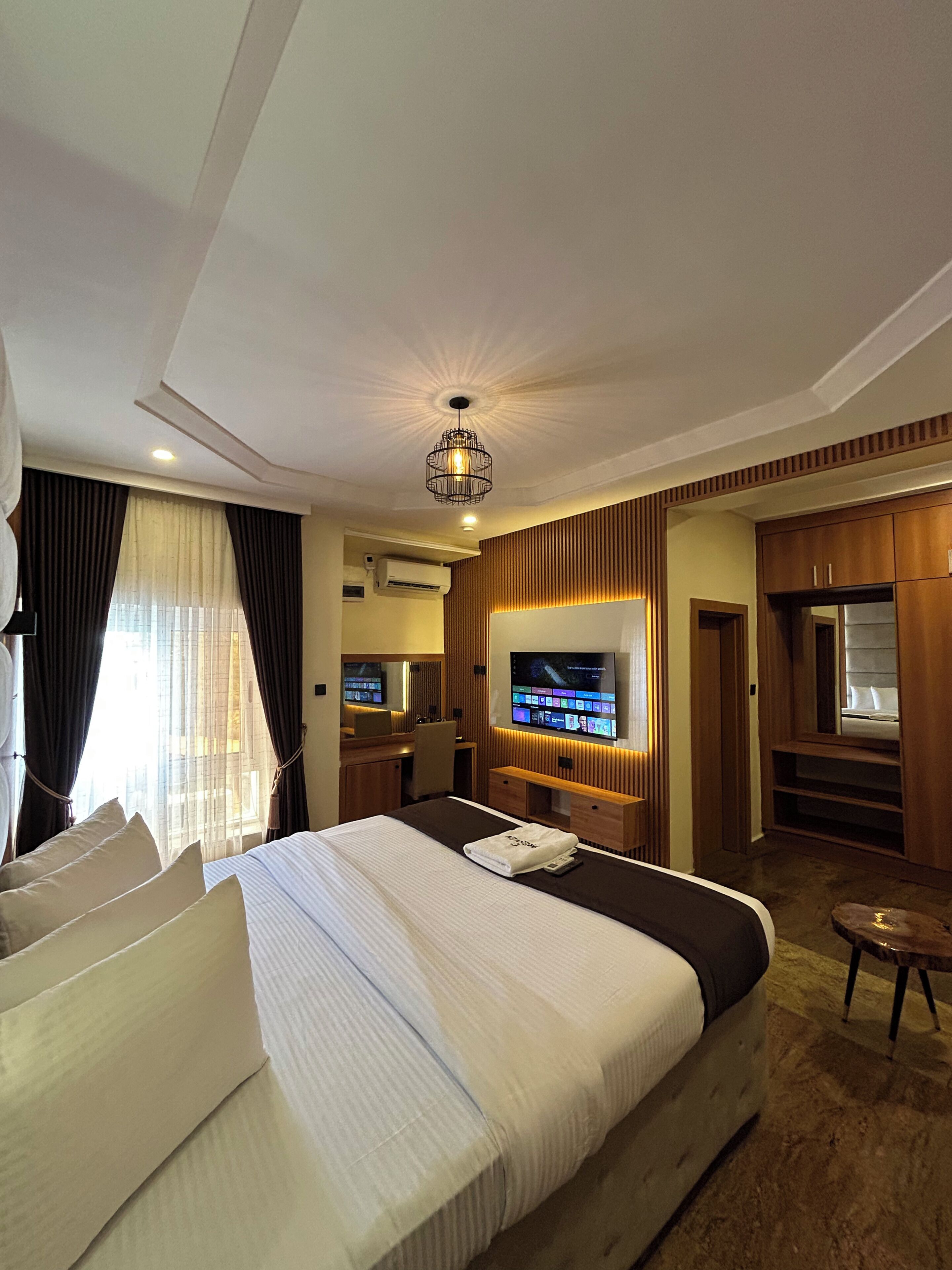 A hotel room with a large bed, a television, a desk, and a mirror.