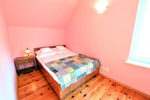 Un dormitorio con una cama de madera, una mesita de noche, una lámpara y una ventana.