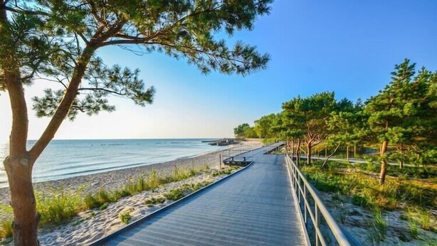 A wooden boardwalk leading to a beach with a clear view of the sea. - Holiday villa with sauna, right on the beach (Ustronie Morskie)