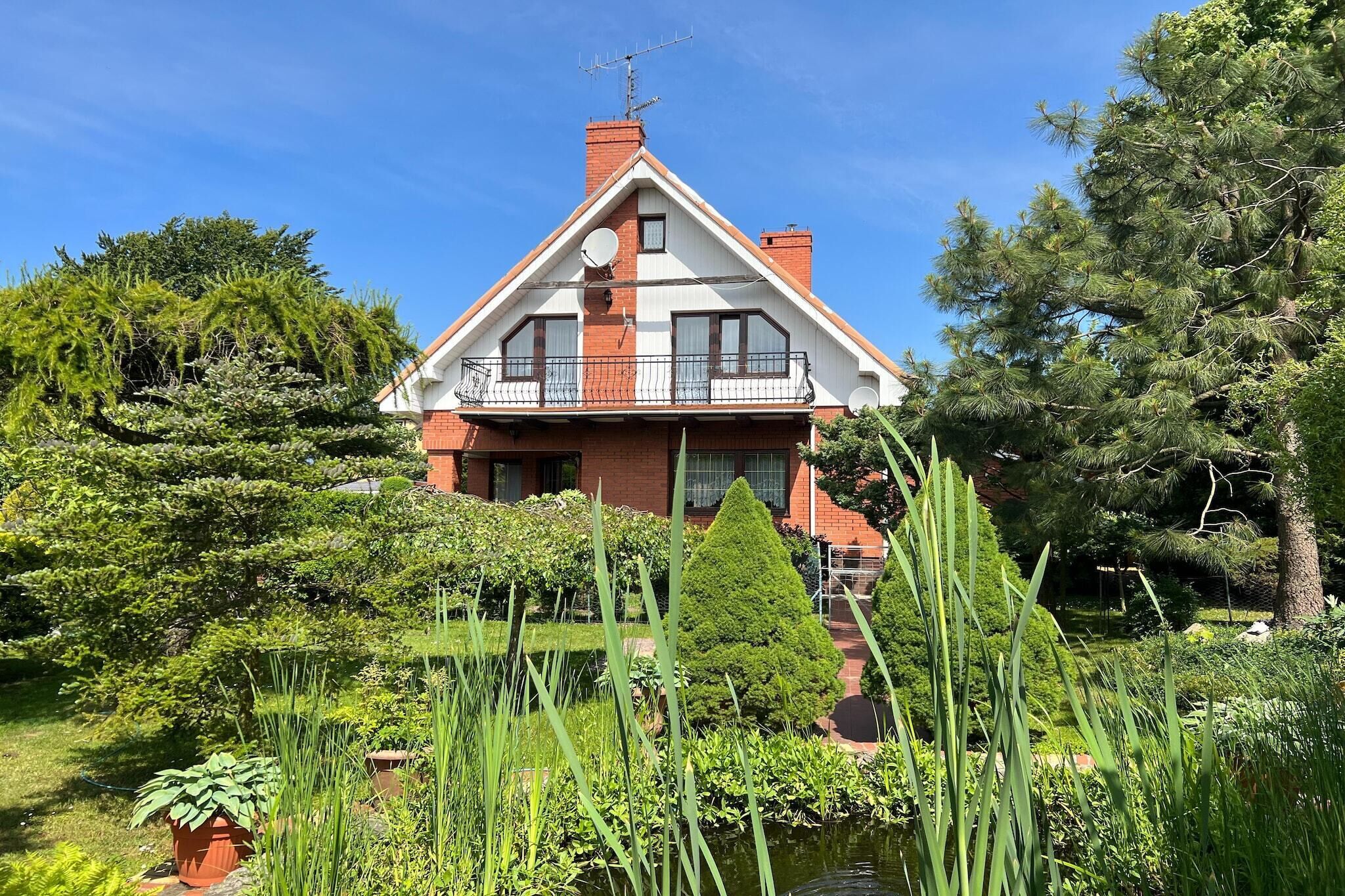 A two-story house with a red brick facade, white trim, and a balcony.