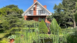 A two-story house with a red brick facade, white trim, and a balcony. - Holiday villa with sauna, right on the beach (Ustronie Morskie)