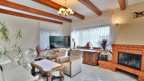 A living room with a fireplace, a TV, and comfortable seating. - Holiday villa with sauna, right on the beach (Ustronie Morskie)