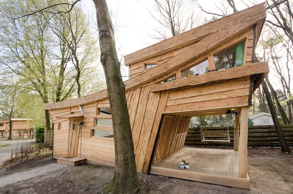 A wooden cabin with a sloped roof, large windows, and a small porch area.