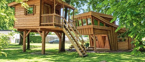 A wooden treehouse with a staircase and a balcony.