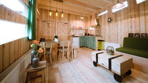 A wooden interior with a dining area, kitchen, and seating space. - Wooden Lodge Victor de Vos | Slapen in een echte boomhut! (Rijen)