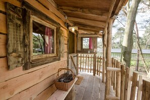 Eine Holzhütte mit Veranda, einem Holzscheitkorb und einem Holzzaun.
