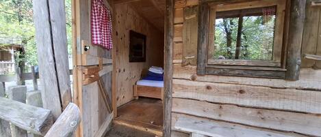 Eine Holzhütte mit einem Bett, einer Bank und einer Fußmatte.