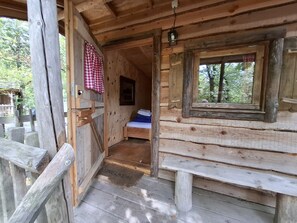 A wooden cabin with a bed, a bench, and a welcome mat.