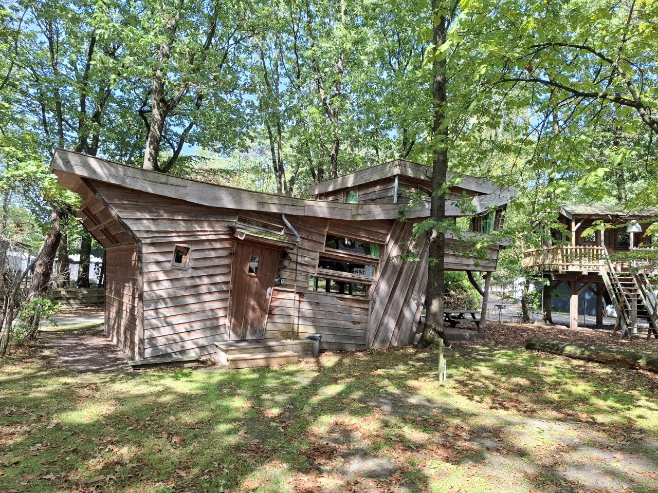 Eine rustikale Holzhütte mit geneigtem Dach, Holzwänden und einer kleinen Veranda.
