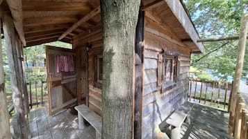 Eine Holzhütte mit Veranda, Bank und Tür.