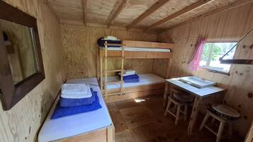 Eine kleine Holzhütte mit Etagenbetten, einem Schreibtisch und einem Fenster.