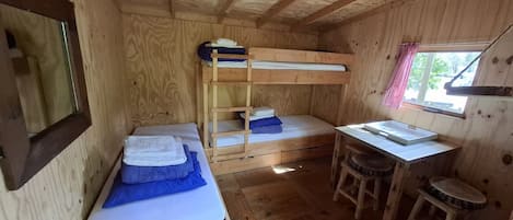 Une petite cabane en bois avec des lits superposés, un bureau et une fenêtre.