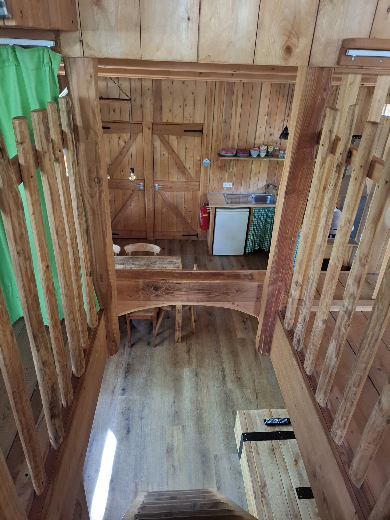 Een houten interieur met een keukenhoek, een eettafel en een trap.