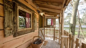 A wooden cabin with a porch, a basket of firewood, and a wooden fence. - Wooden Lodge Victor de Vos | Slapen in een echte boomhut! (Rijen)