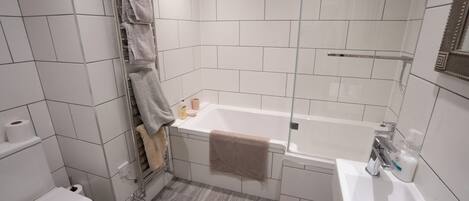A modern bathroom with a toilet, bathtub, and sink.