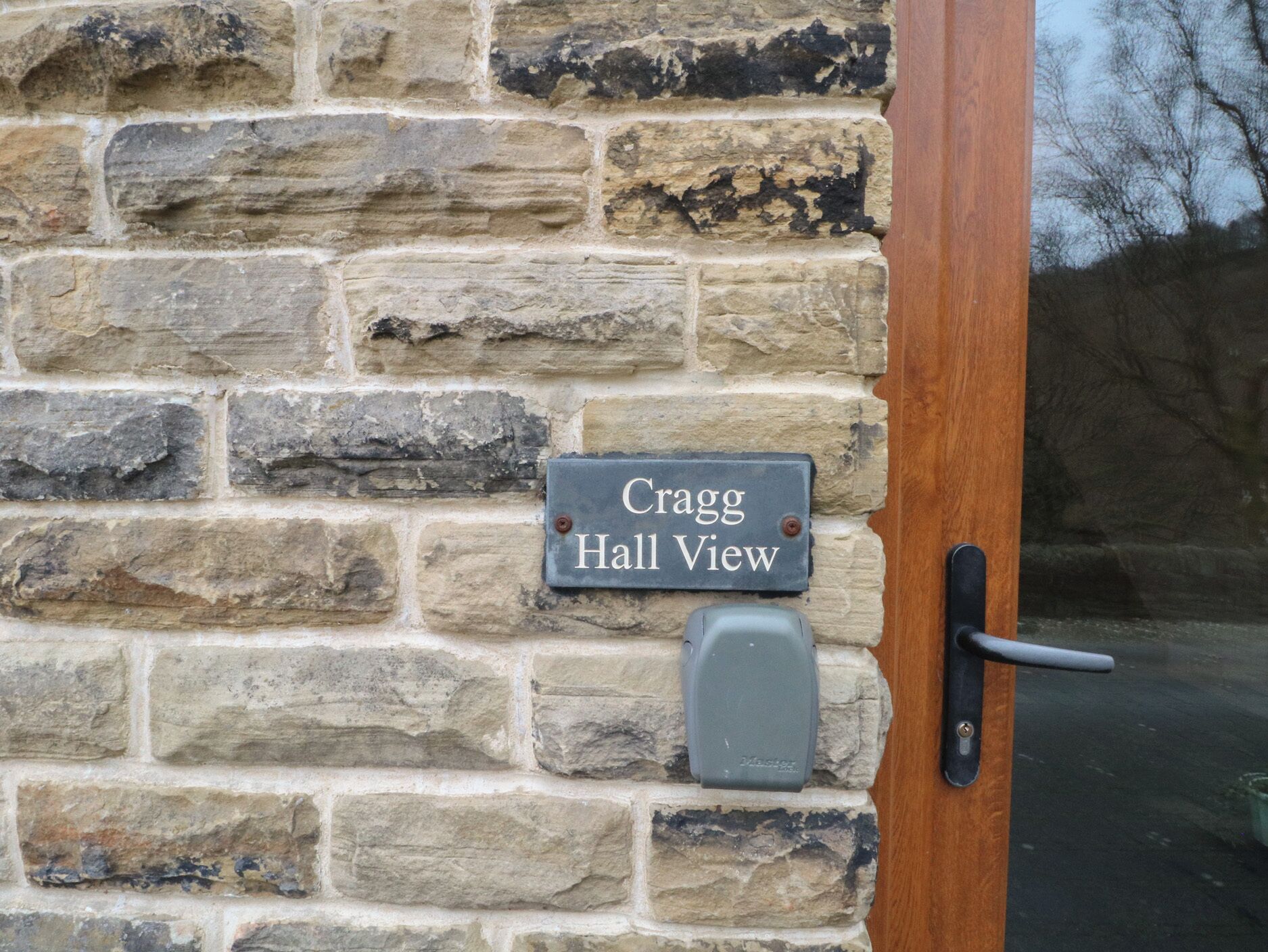 Un mur de pierre avec une pancarte indiquant « Vue sur Cragg Hall » et une poignée de porte.