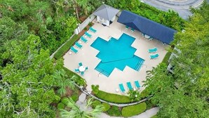 An aerial view of a resort with a large swimming pool, lounge chairs, and a covered seating area surrounded by lush greenery. - Beach Square 3 –optional BIKES – Walk 2 Redfern Village, shops, and restaurants! (St. Simons Island)