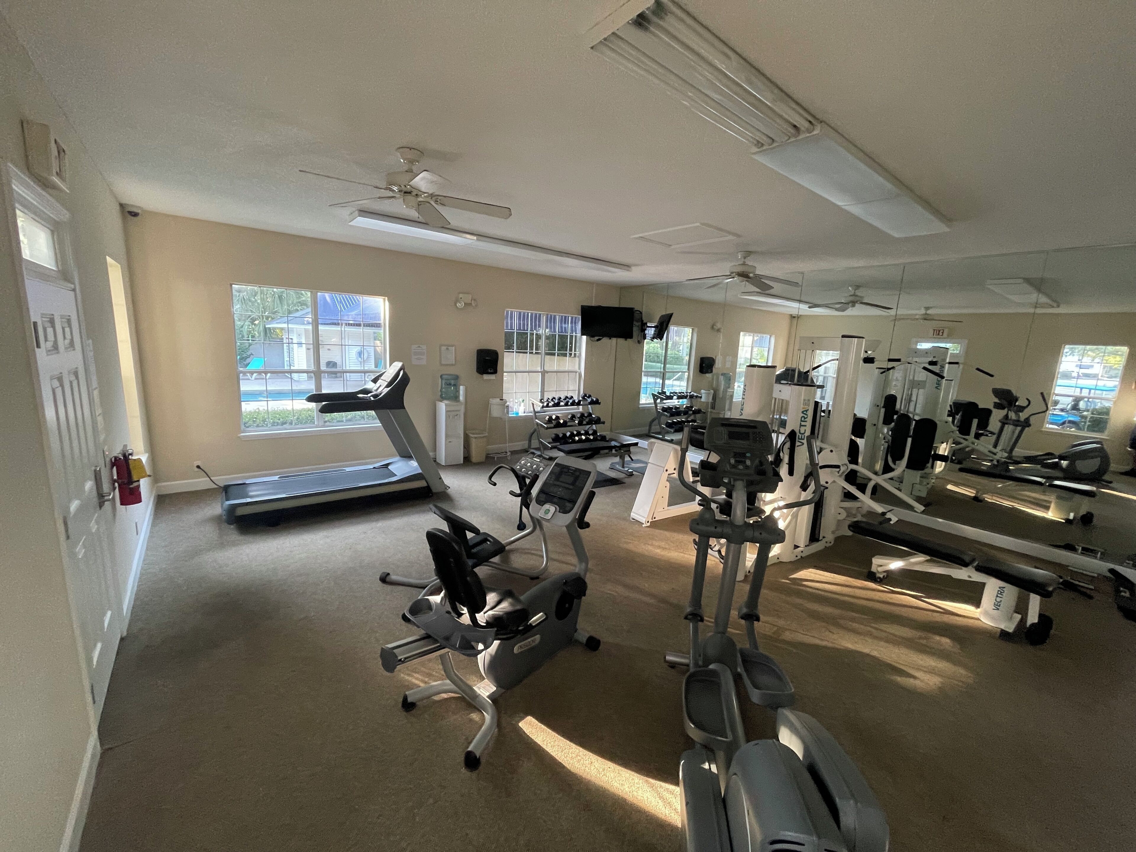 Une salle de sport équipée de tapis de course, de vélos elliptiques et de matériel de musculation.