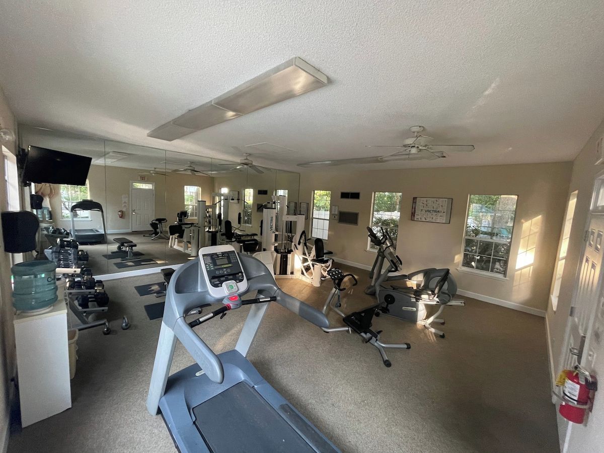 A gym with cardio equipment, weight machines, and a mirrored wall.