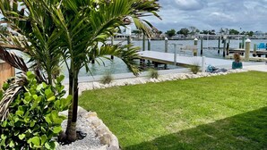 A marina with a dock, a grassy area, and a palm tree. - Waterfront Escape - Beach + Golf Cart + Family Memories - Indian Rocks Beach, FL (Indian Rocks Beach)