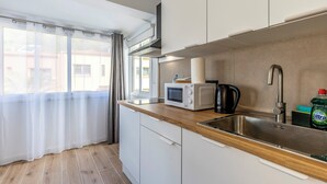 Et moderne køkken med træbordplade, stålvask og hvide skabe.