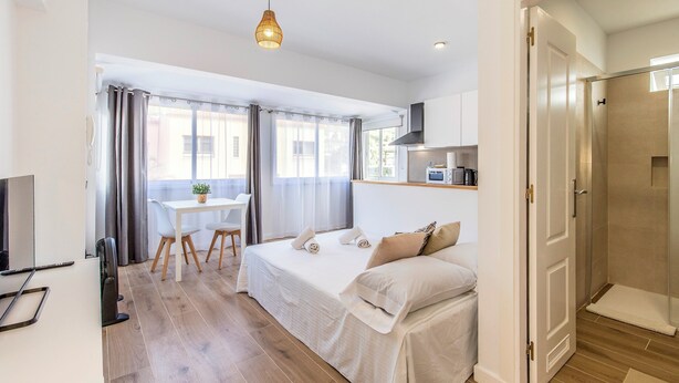 Et moderne hotelværelse med en seng, et sengebord og et lille skrivebord med en stol.
