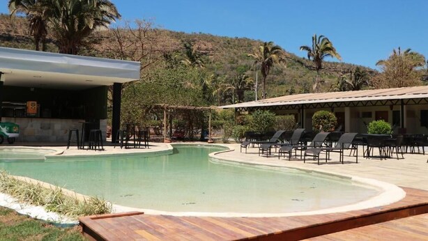 A pool area with lounge chairs and a building with a flat roof. - Pousada Casa de Naná (Palmas)