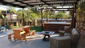 An outdoor patio with wooden furniture, including a table and benches, and wicker sofas. - Pousada Casa de Naná (Palmas)