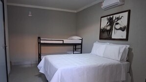 A bedroom with a bunk bed, a single bed, a desk, and a wall-mounted air conditioner. - Pousada Casa de Naná (Palmas)