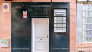 A white door with a brass handle, a black metal frame, and a small window with horizontal bars. - M (IRI70) Cozy Duplex in the Salamanca district (Madrid)