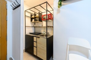 A compact kitchen with a built-in microwave, a sink, and a small countertop. - M (IRI70) Cozy Duplex in the Salamanca district (Madrid)