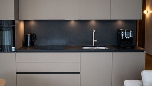 Een moderne keuken met een ingebouwde koffieapparaat, een waterkoker en een spoelbak.