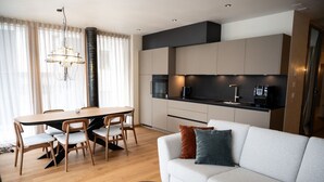 Een moderne woonkamer met een bank, salontafel, eettafel en stoelen.