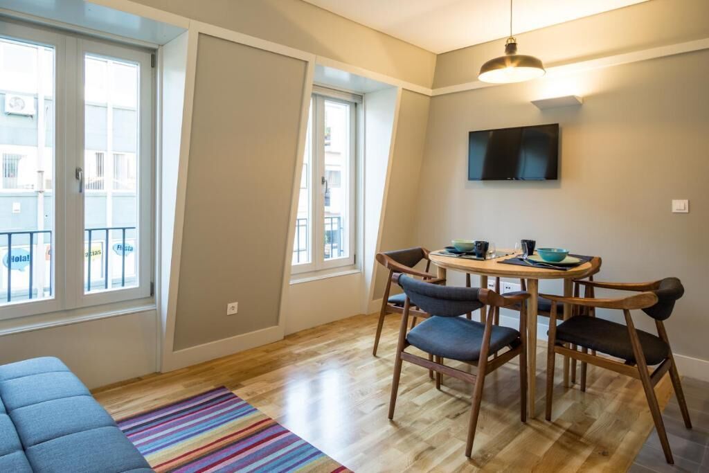A modern apartment with a dining area, a sofa, and large windows.