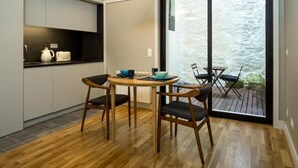 Una cucina compatta con angolo pranzo, un'ampia porta scorrevole in vetro che dà su un terrazzo esterno e una lampada a sospensione sopra il tavolo.
