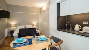 Camera d'albergo compatta con angolo ristoro, angolo cottura e un letto con comodino.