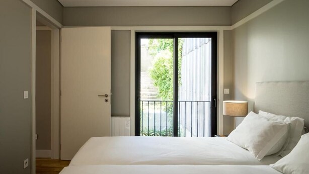Una camera d'albergo con un letto grande, una porta che dà su un balcone e una lampada sul comodino.