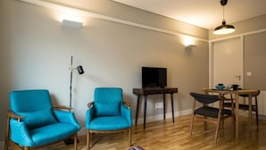 Un soggiorno con due poltrone blu, un tavolino in legno, una televisione e un tappeto a righe.
