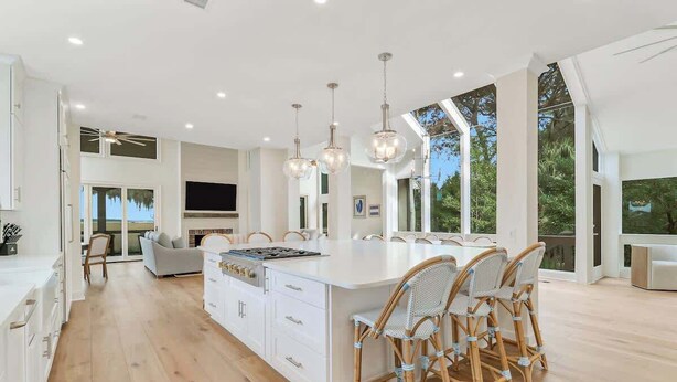 A modern kitchen with a large island, white cabinetry, and wicker chairs. - Private Marshfront Oasis w/ Pool & Sunset Views (Hilton Head Island)