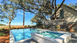 A swimming pool with a hot tub, surrounded by trees and a brick house with a balcony. - Private Marshfront Oasis w/ Pool & Sunset Views (Hilton Head Island)