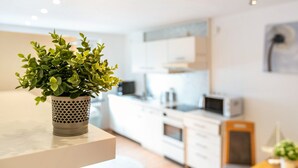 A modern kitchen with white cabinets, a microwave, and a potted plant on a counter. - Apartment 'Seestern' with Balcony and Wi-Fi (Wester-Ohrstedt)