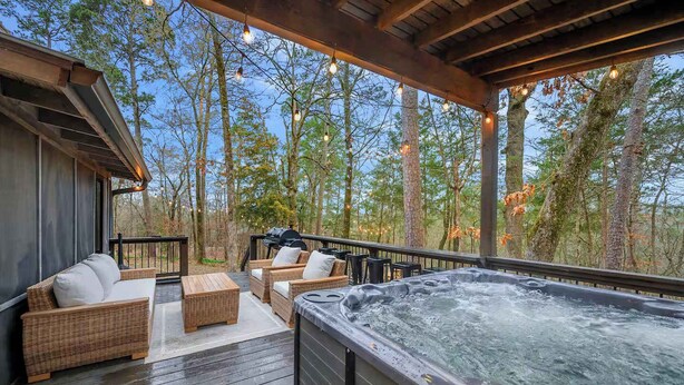 An outdoor deck with wicker furniture, a hot tub, and a grill. - Sleeps 18 - Hot Tub - Playground - Games - Firepit (Broken Bow)